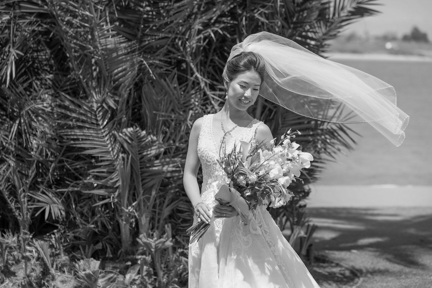 A black and white photo of a bride in a wedding dress holding a bouquet of flowers.