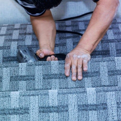A man is installing a carpet on stairs with a machine.
