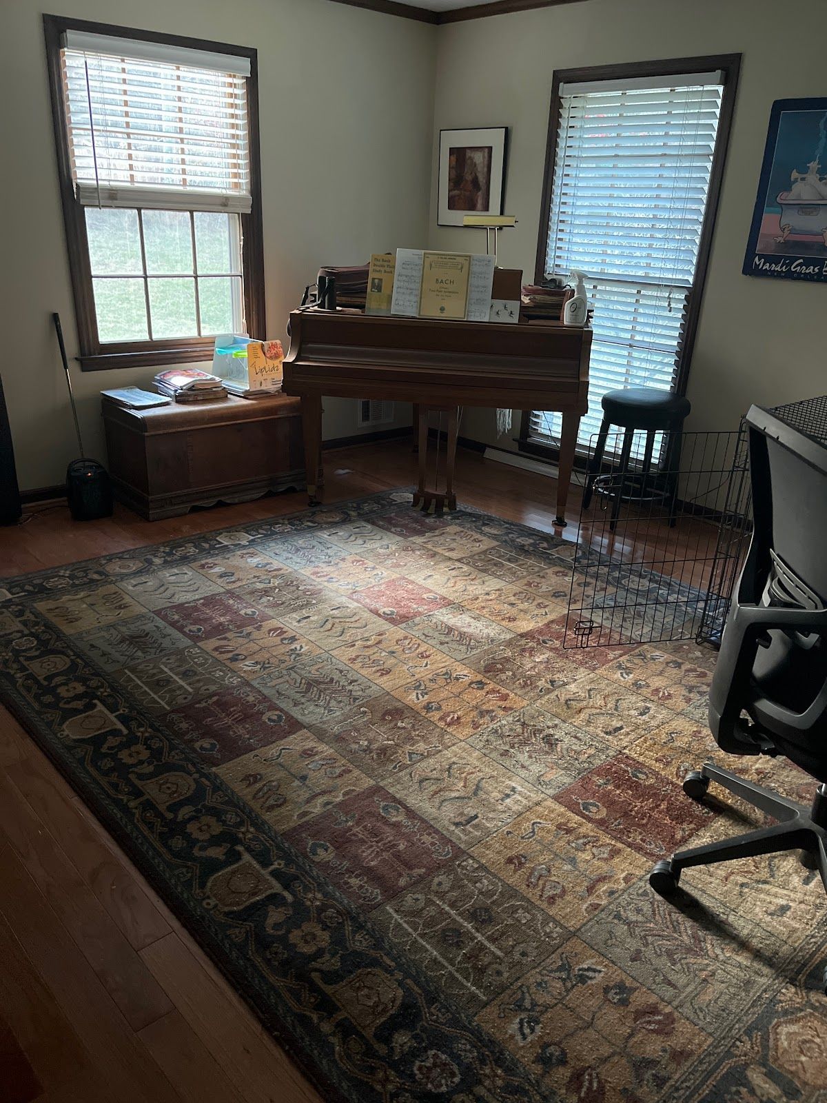 A room with a rug , a piano , a desk and a chair.