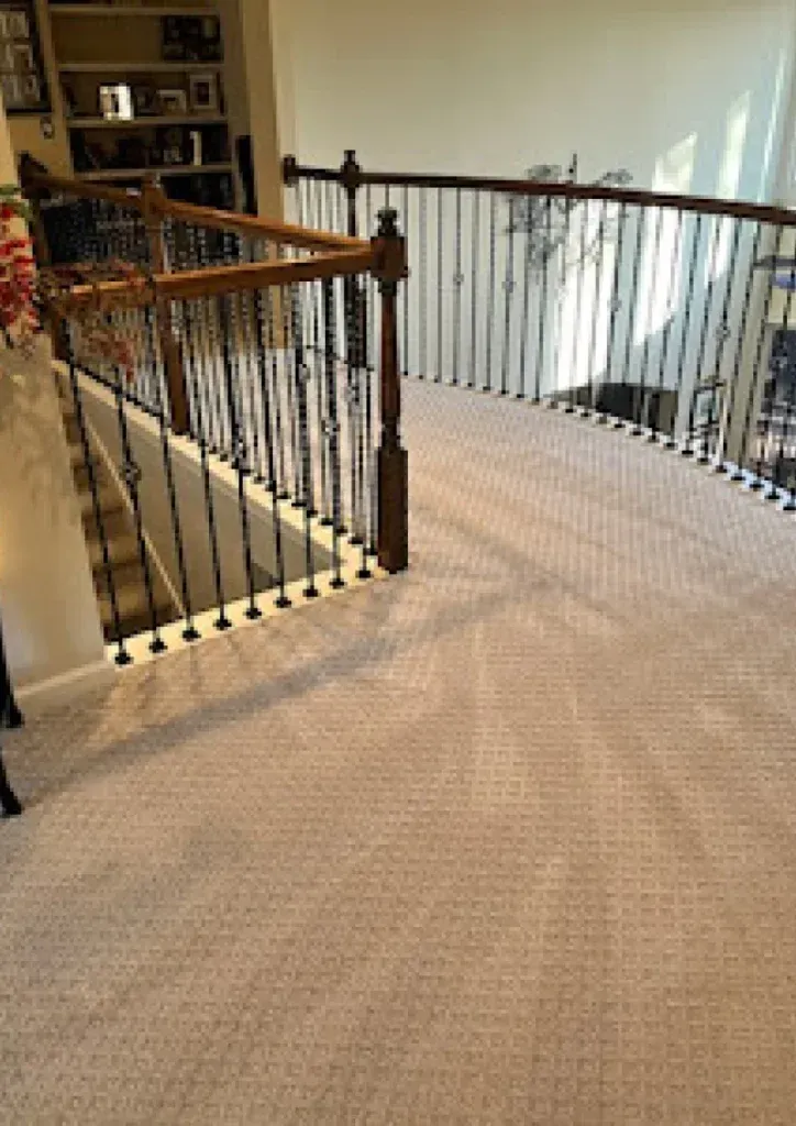 A staircase with a wooden railing and a carpeted floor in a house.