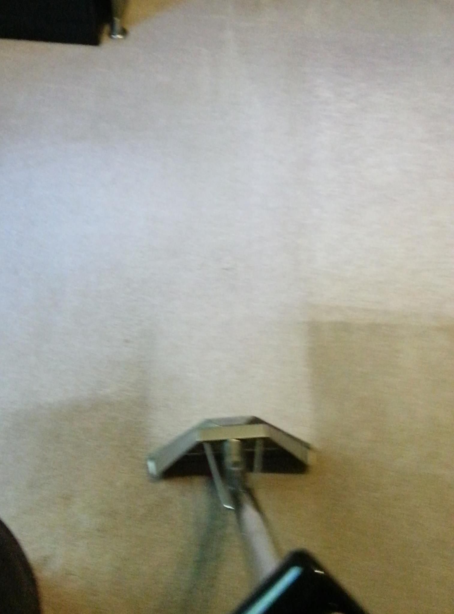 A person is cleaning a carpet with a vacuum cleaner.