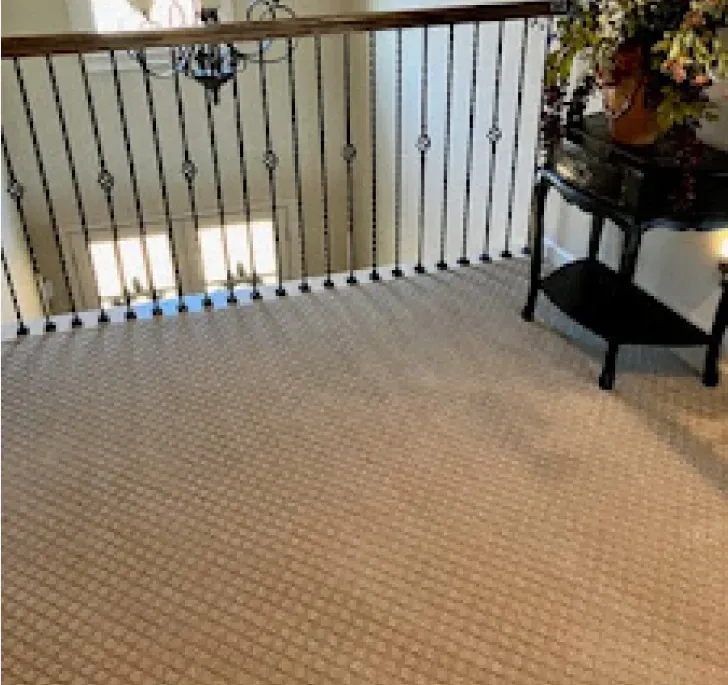 A staircase with a wrought iron railing and a table with a vase of flowers on it.