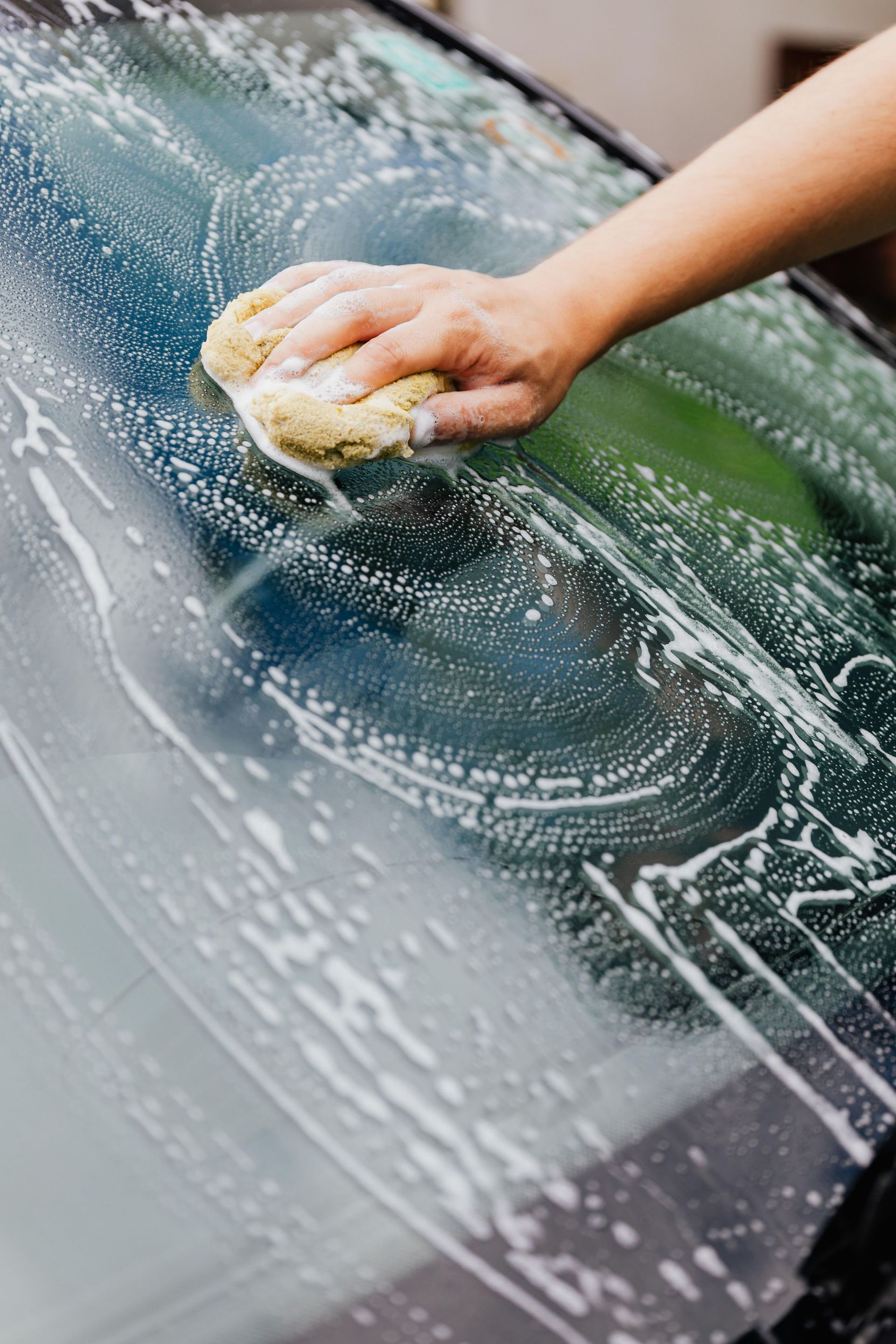 a person washing a car windshield by Wax On