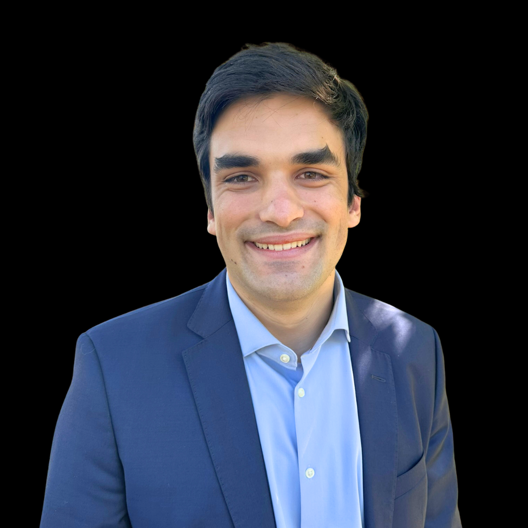Man in a blue suit smiling, set against a black background.