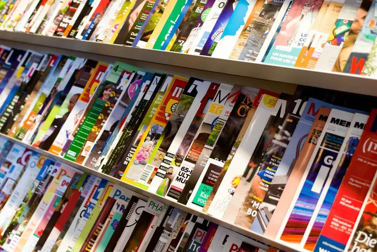 Tijdschriften uitgestald op planken, diverse kleurrijke omslagen.