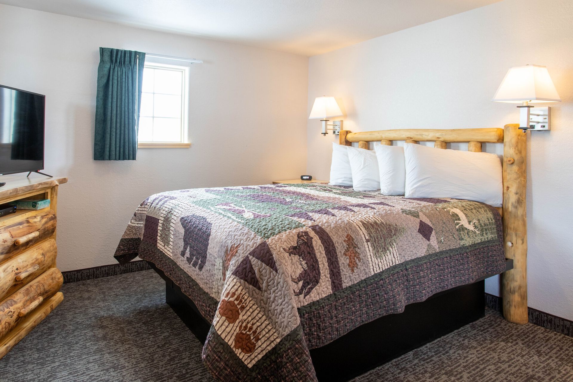 Bedroom with a bed, TV, and wood furniture. Bed has a quilt with bear motifs.
