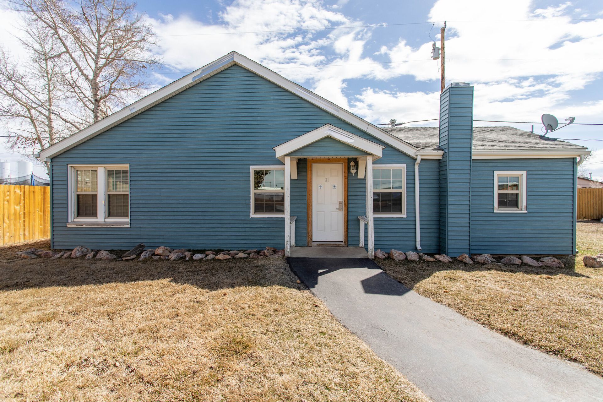 The front of a blue house with a walkway leading to it.