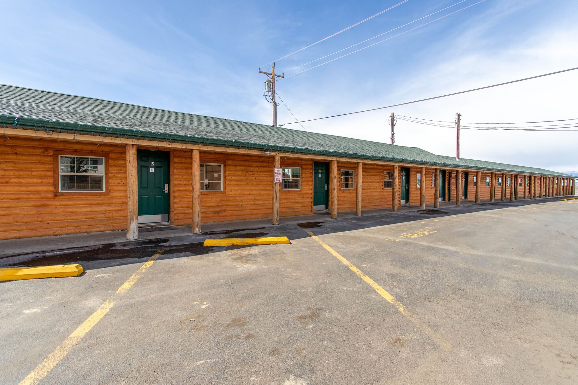A motel with a lot of rooms and a parking lot in front of it.