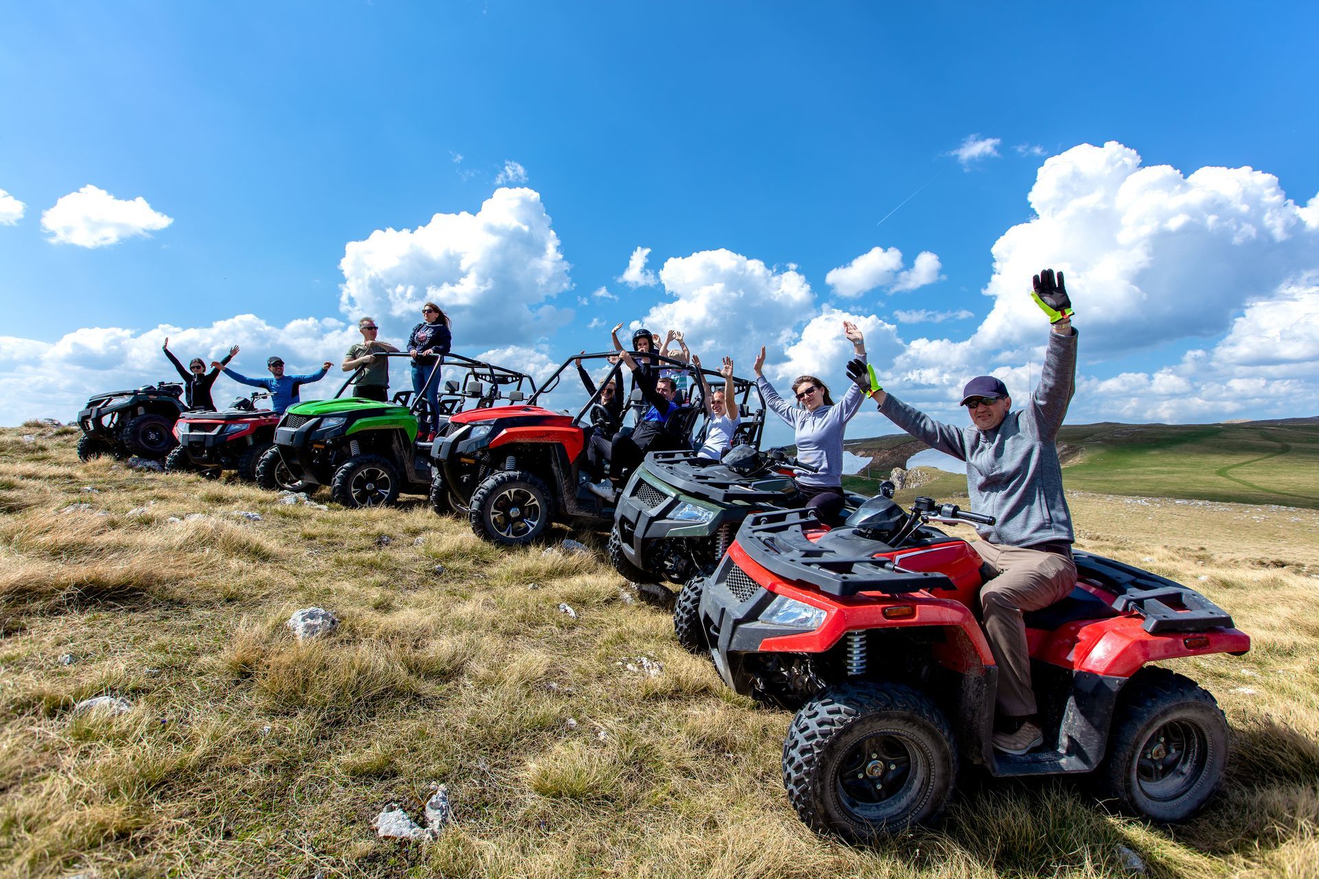 A group of people are standing next to each other on atvs in a field.