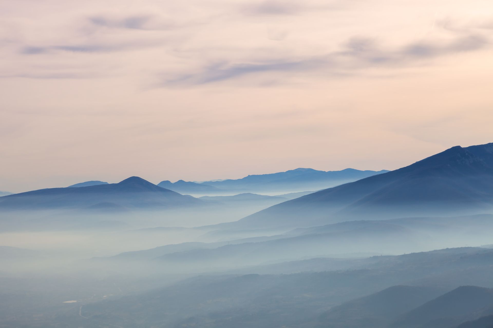 A view of a mountain range covered in fog at sunset.