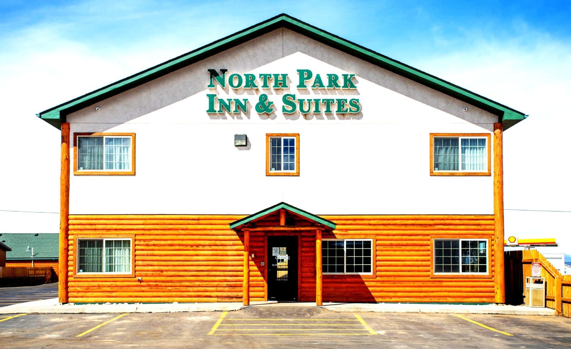 North Park Inn & Suites hotel with light brown wood siding and green trim.