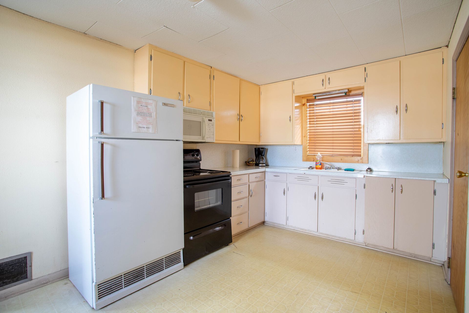 Kitchen with white appliances, light cabinets, and beige walls.