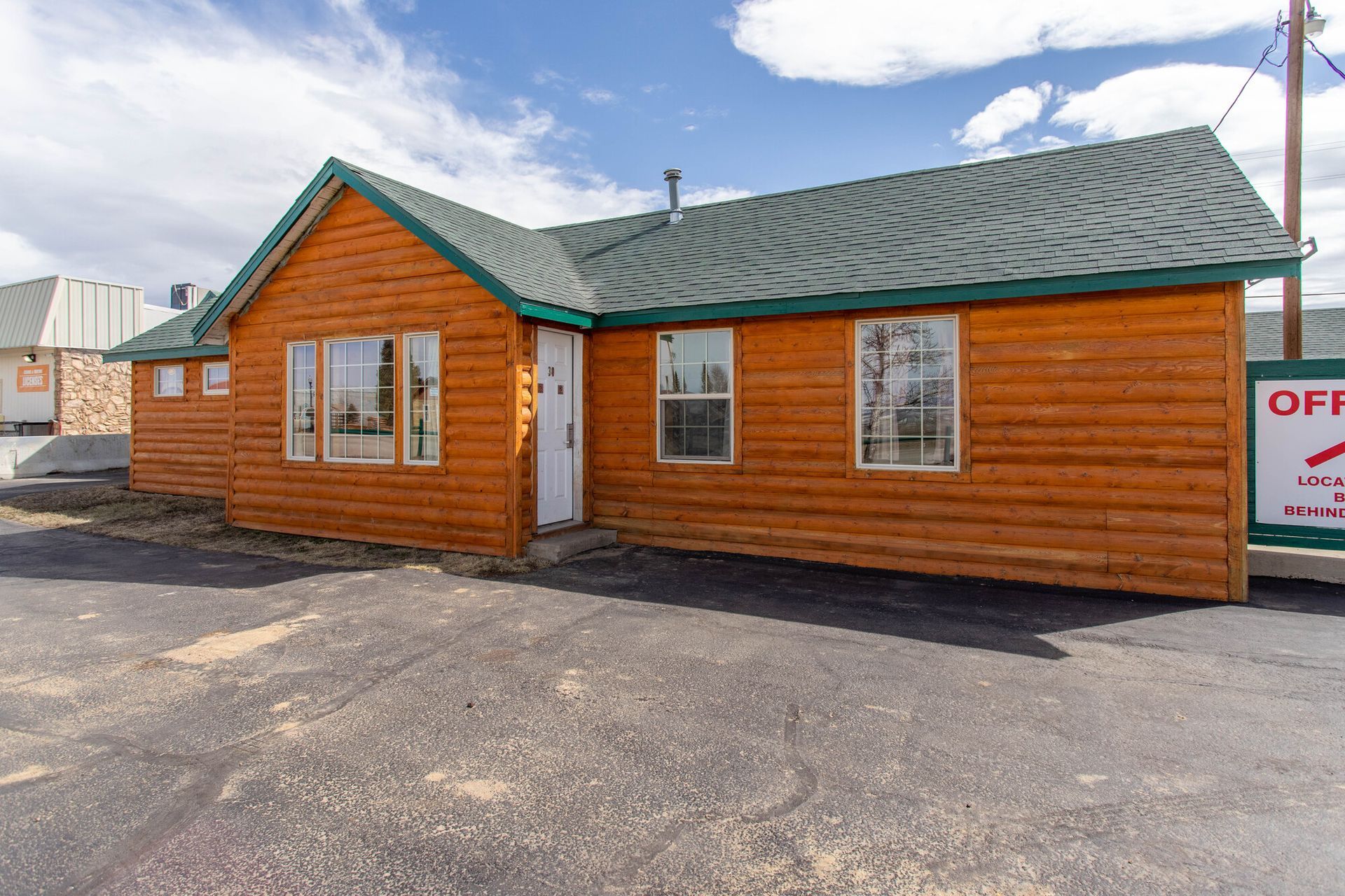 A small wooden house with a green roof is for sale.