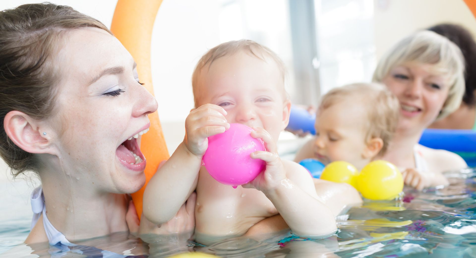 Child learning to swim with instructor in indoor pool