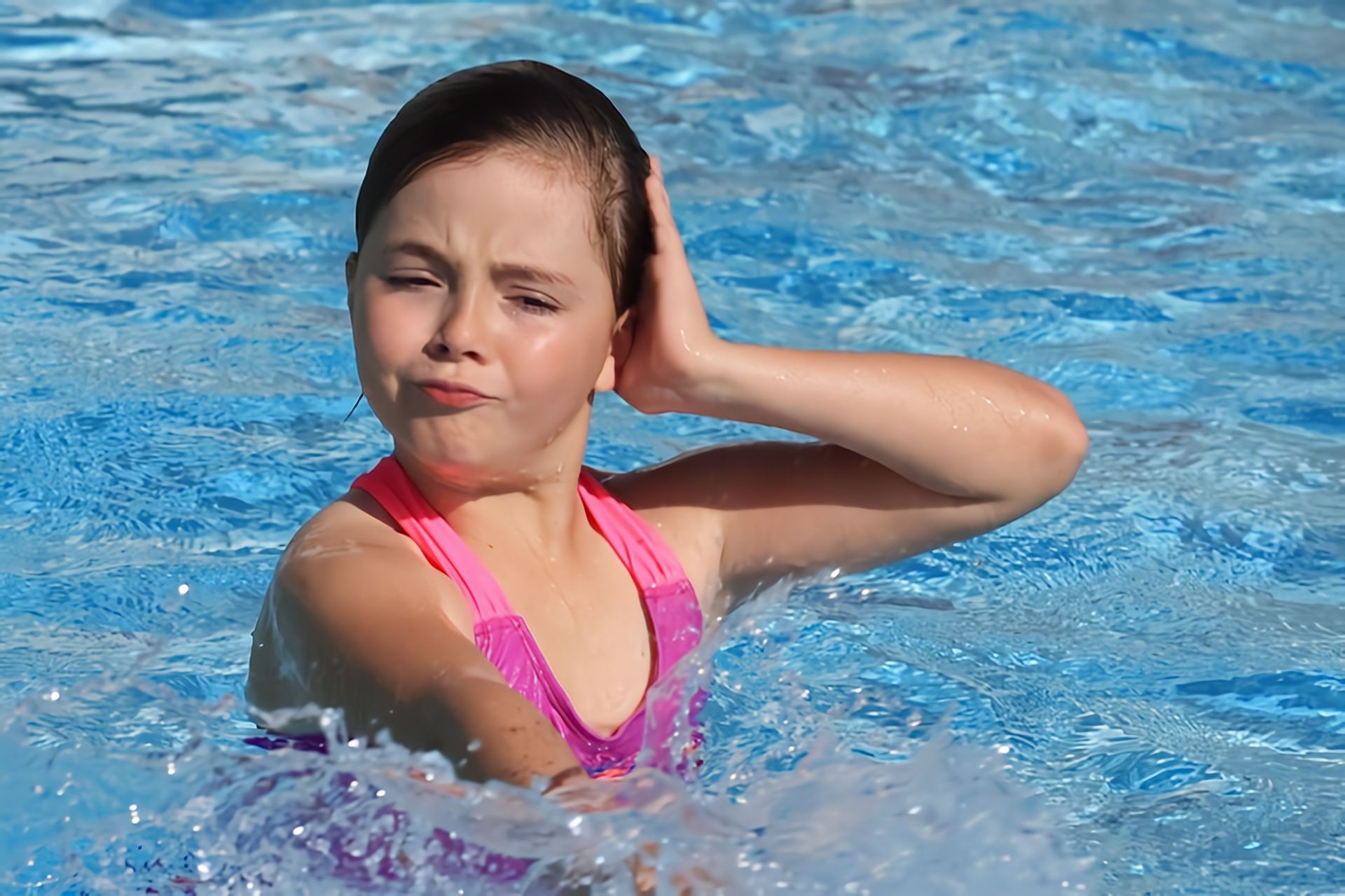 A child practicing kicking in a bright blue pool
