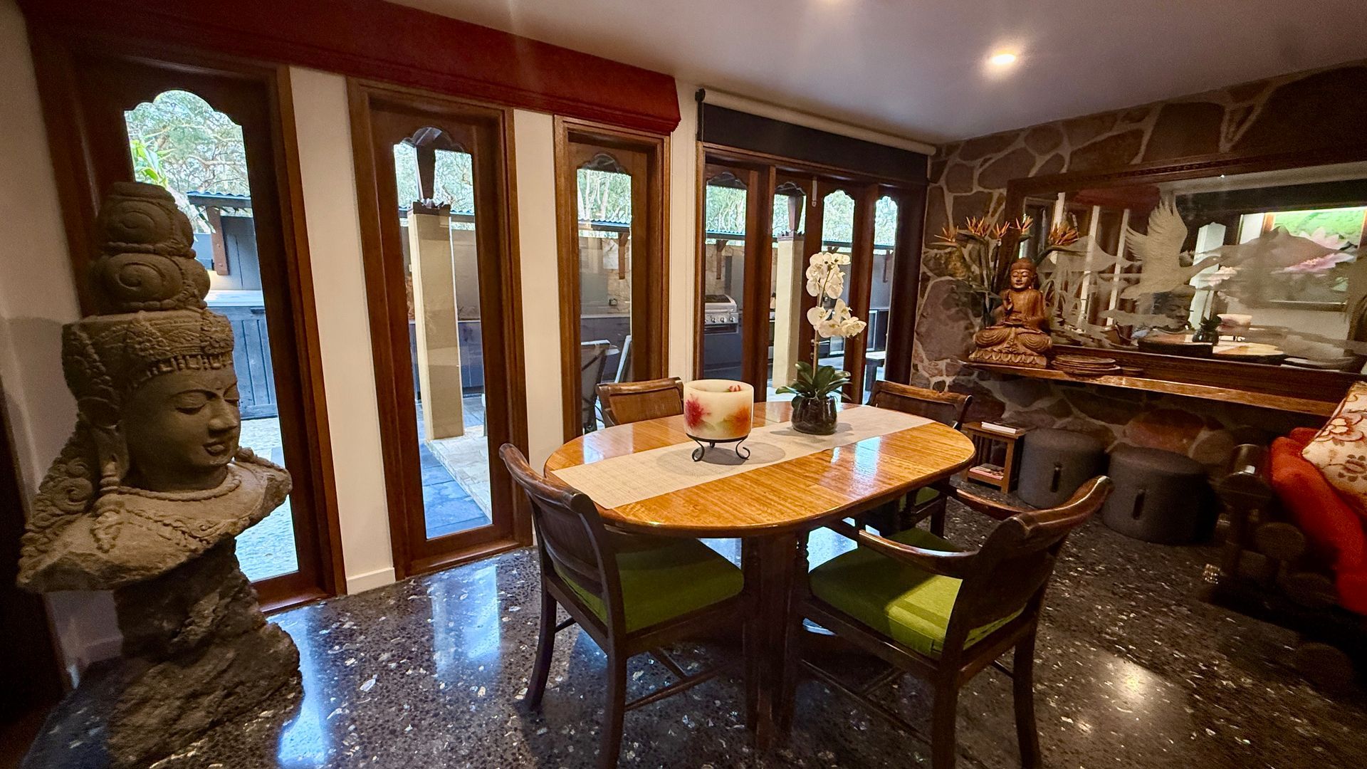 Dining room with antique decor, Buddha statue, wooden furniture, and stone walls — Bali at the Bay in Nelson Bay, NSW