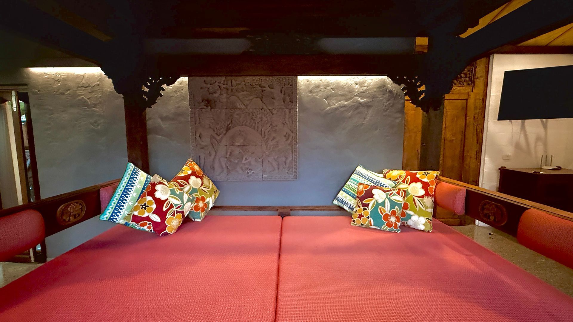 A bed with red mattress, colourful pillows, and a dark wooden canopy — Bali at the Bay in Nelson Bay, NSW
