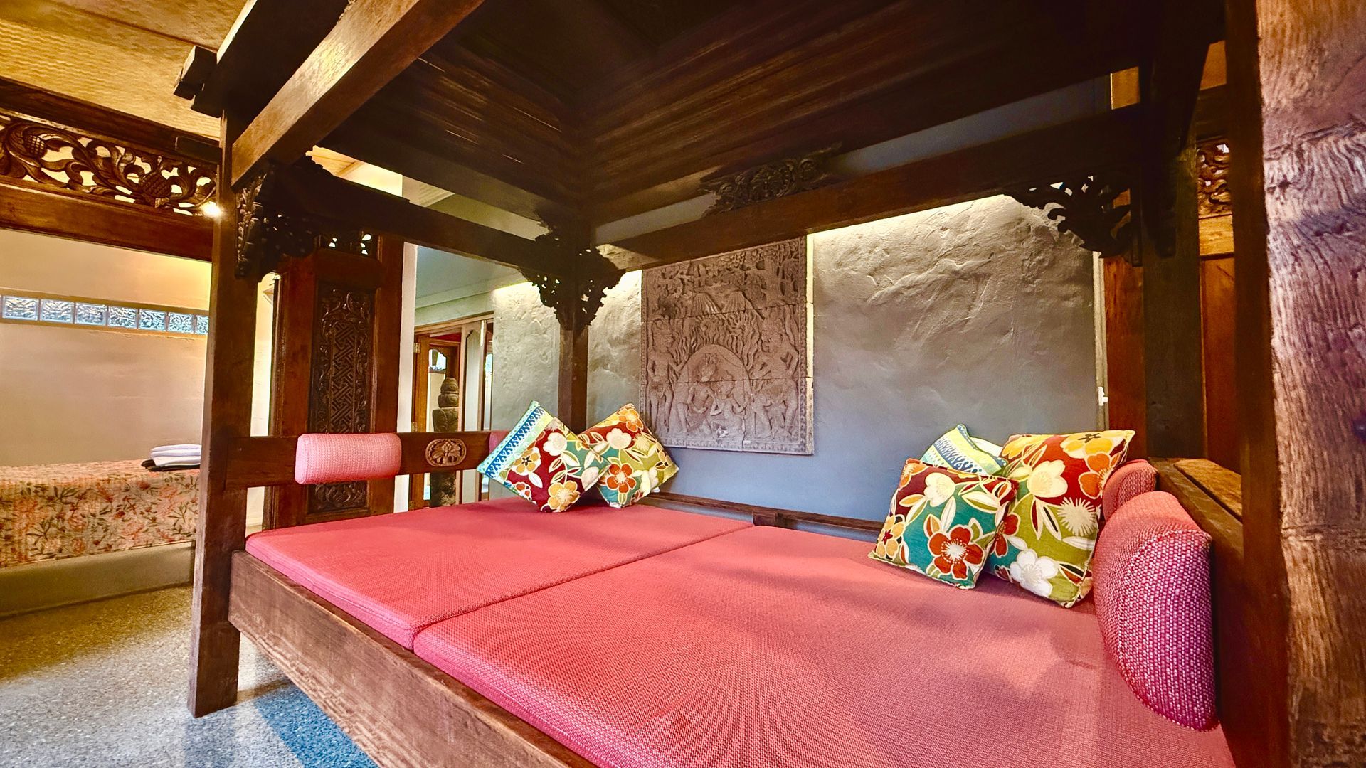 Wooden canopy bed with pink cushions — Bali at the Bay in Nelson Bay, NSW