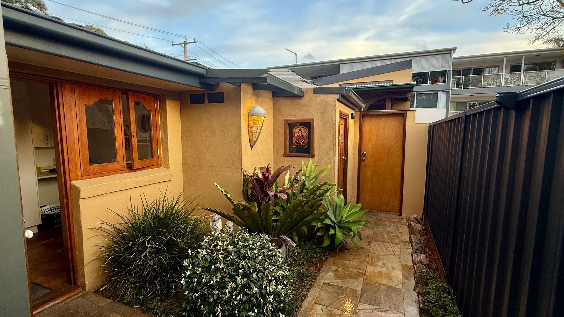 Exterior view of a tan building with wooden doors and windows — Bali at the Bay in Nelson Bay, NSW