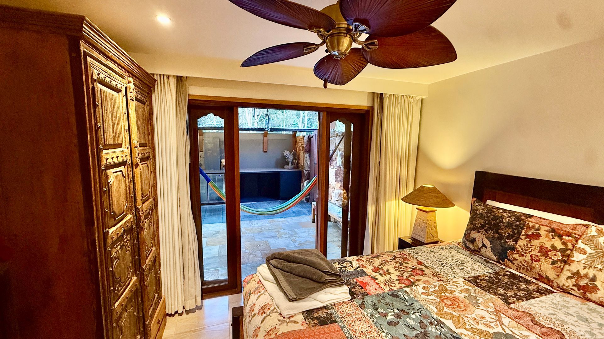 Bedroom with open doors to a patio. Features a bed, wardrobe, and ceiling fan — Bali at the Bay in Nelson Bay, NSW