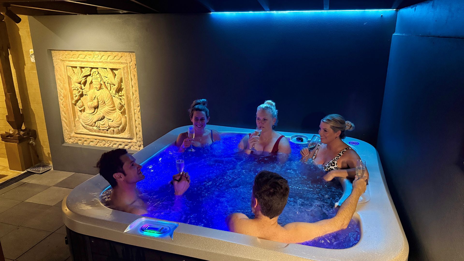 Five people in a lit hot tub, posing for a photo — Bali at the Bay in Nelson Bay, NSW