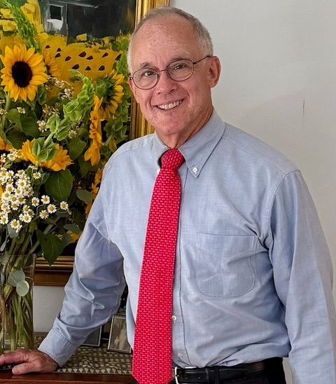 Photo Ned Forney in shirt and tie, with sunflowers behind him