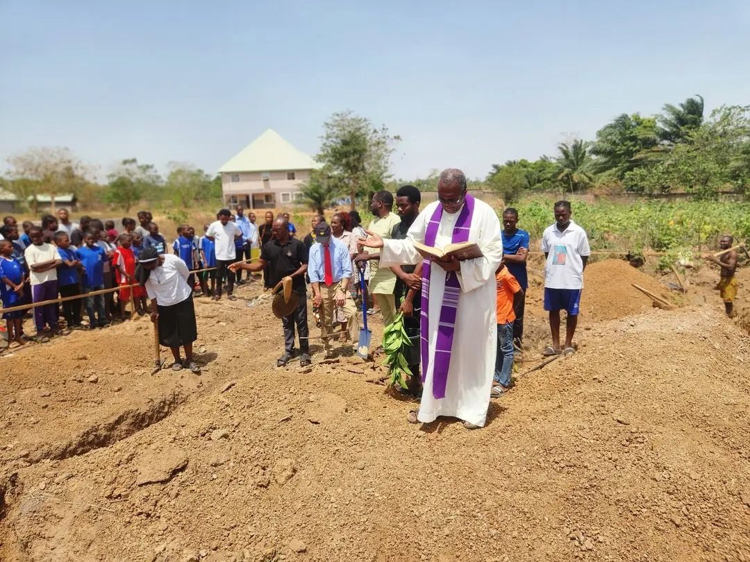 Group of people in Africa surrounding a priest who is blessing the ground