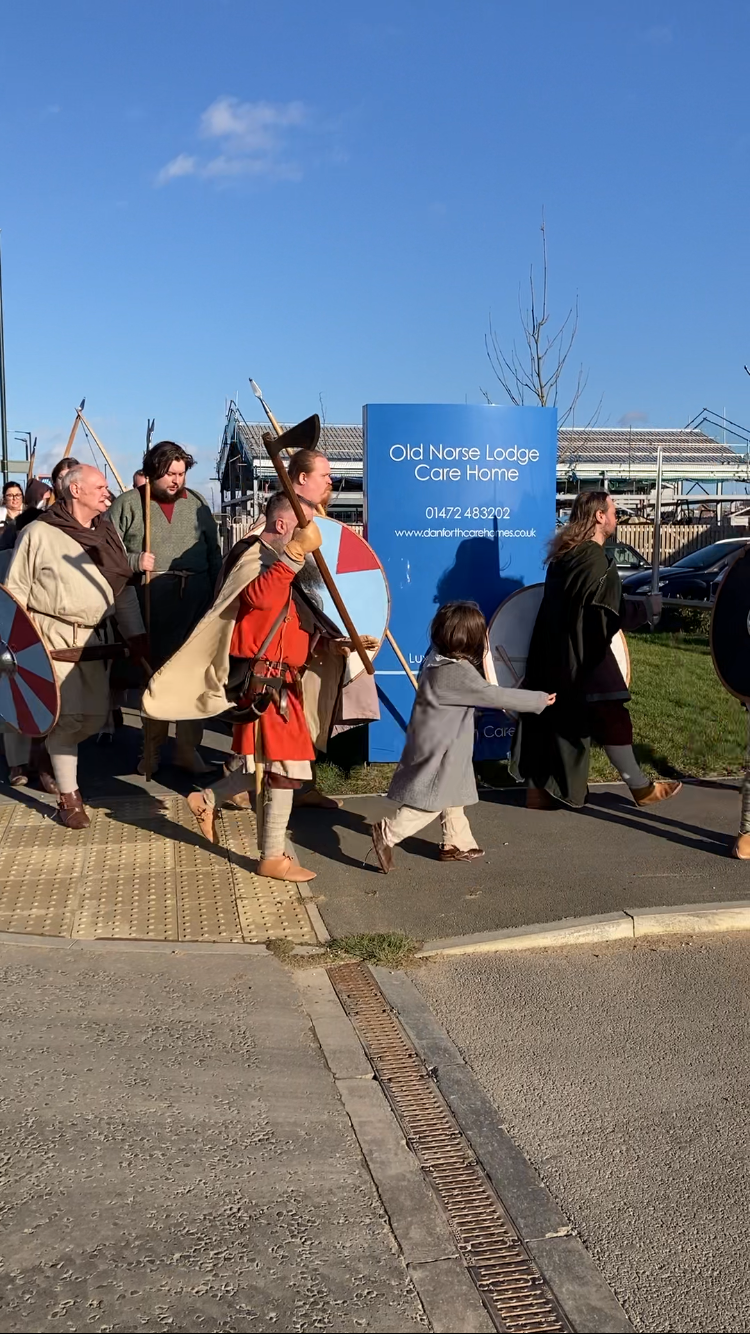 A group of people dressed in medieval costumes are walking down a sidewalk.