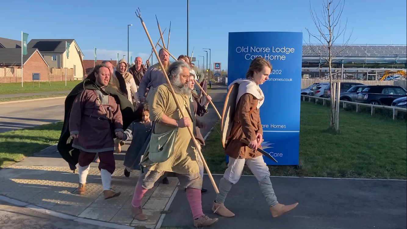 A group of people dressed in medieval costumes are walking down a street.
