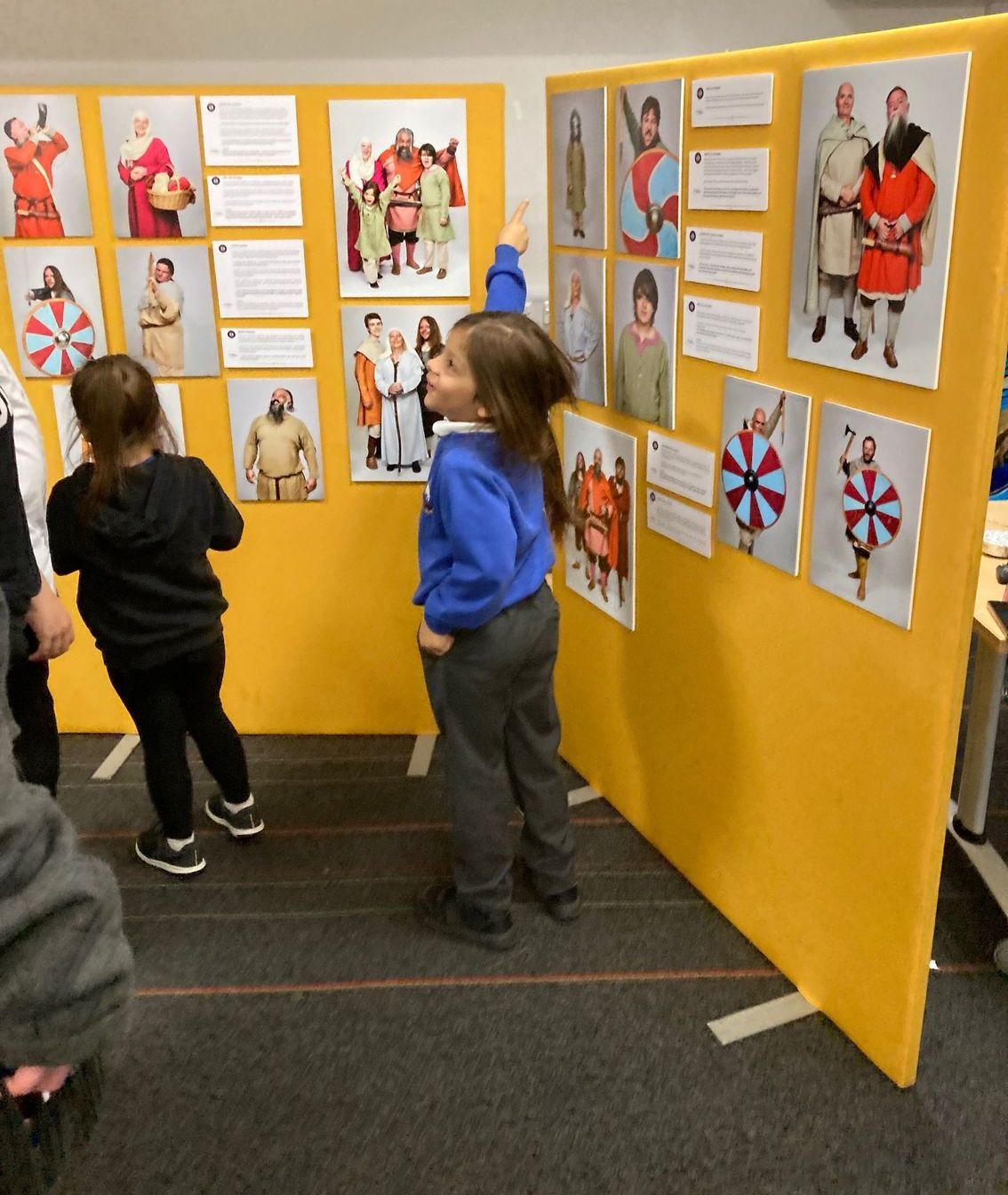 A group of children are looking at pictures on a wall