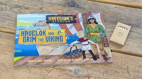 A book called havelok and grim the viking is sitting on a wooden table.
