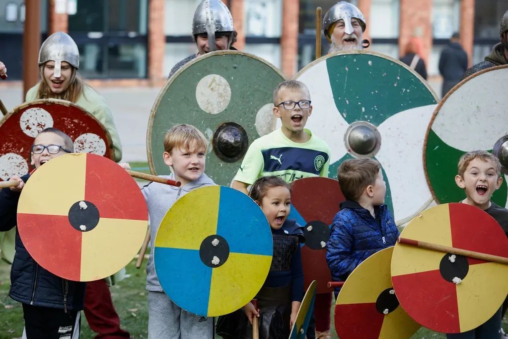 A group of children are wearing viking costumes and holding shields.