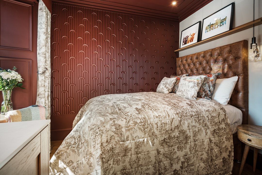 A bedroom with a bed and a desk with a laptop on it.