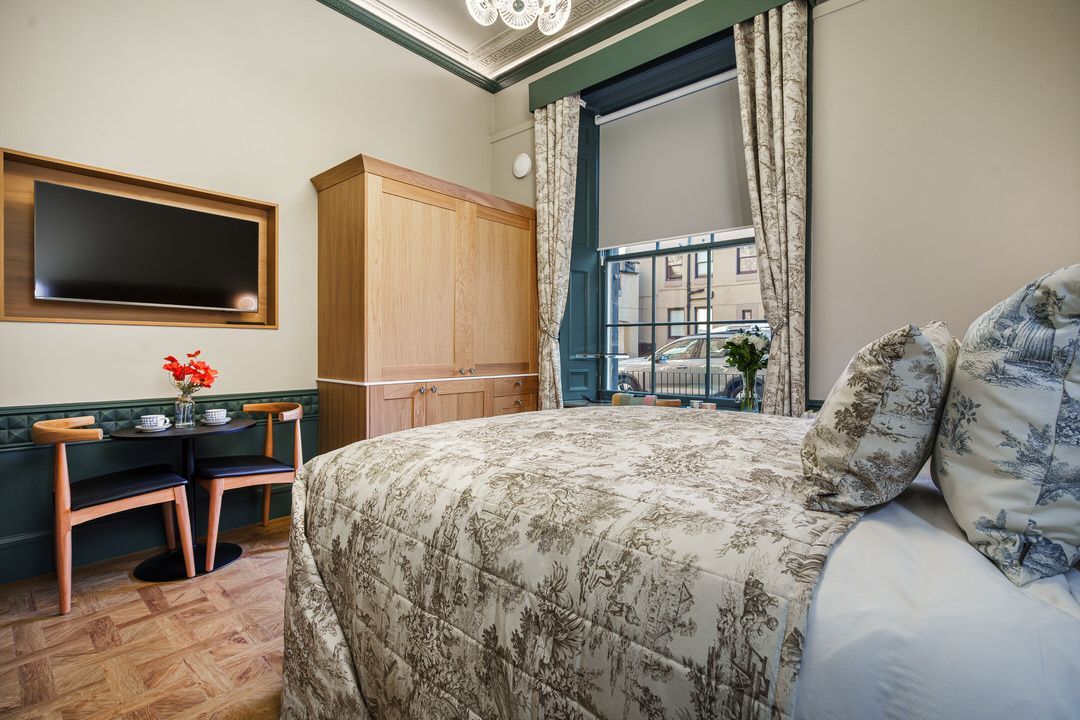 A bedroom with a bed , chair , desk and television.