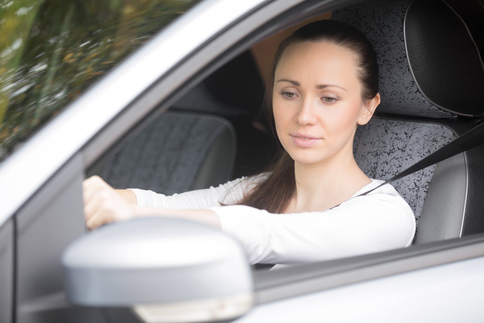Teen in car looking in side view mirrors