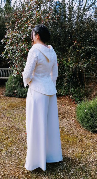 Woman showing the back of her wedding outfit. Ivory top and ivory trousers