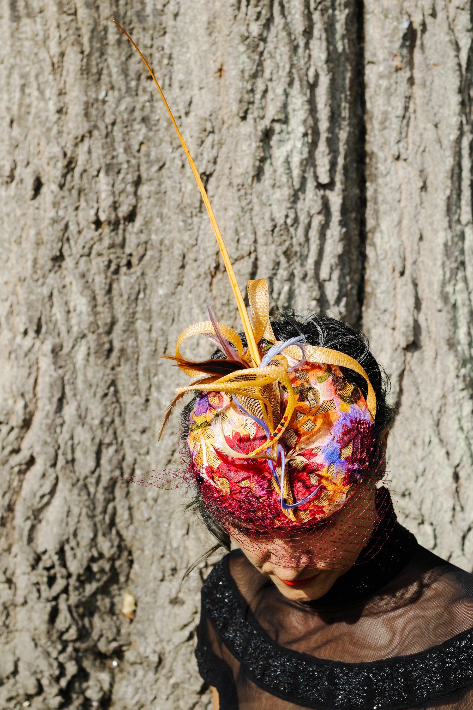 the model wears a navy beret  made in sinamay. Trimmed with feathers and  net covering her eyes.
