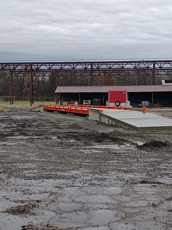 A muddy, industrial scene featuring a concrete ramp leading to a loading dock.
