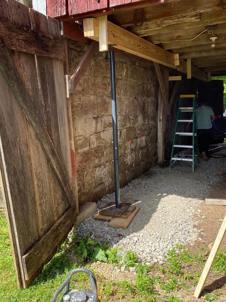 A barn doorway being supported by a metal jack.