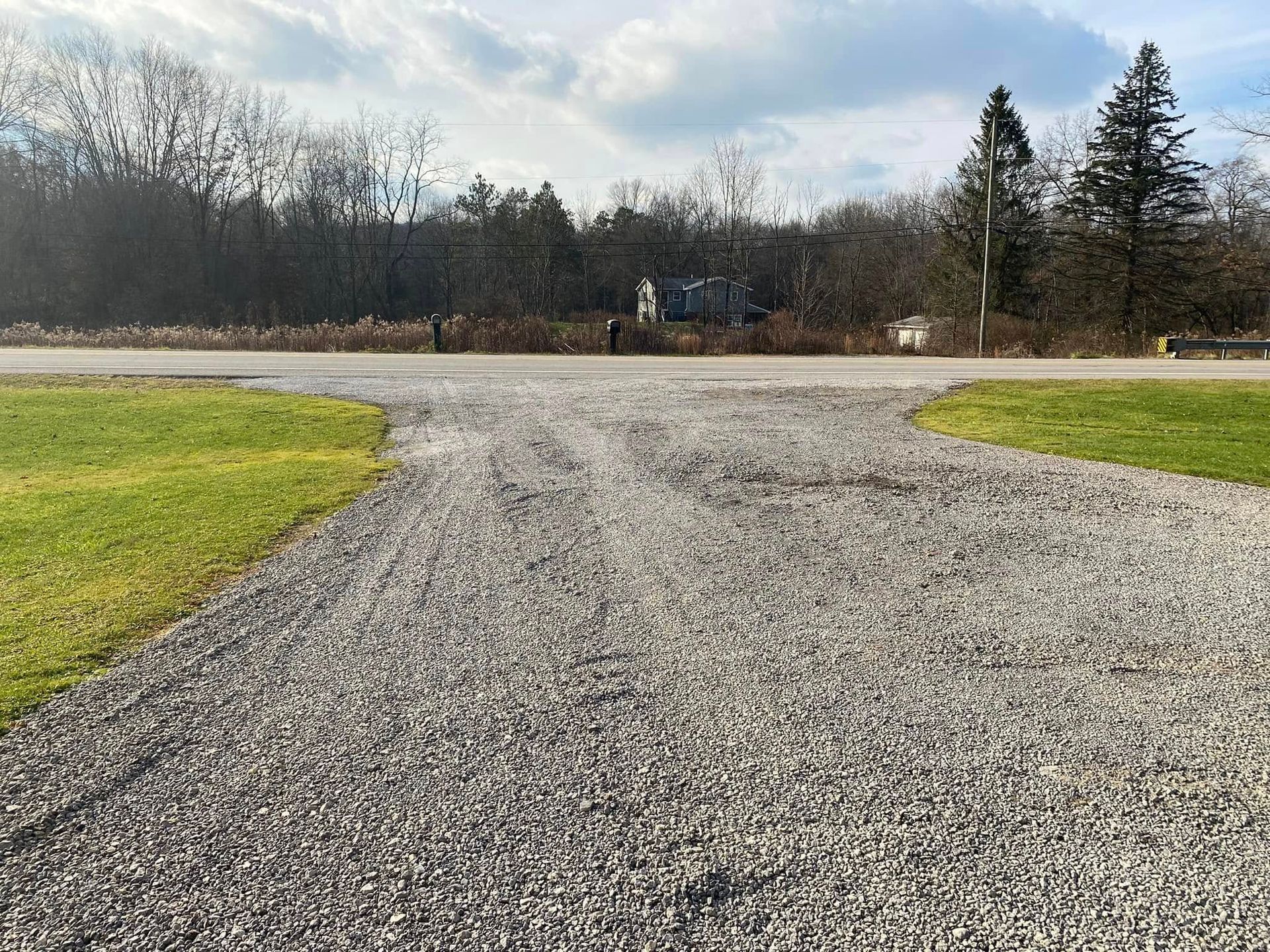 Gravel driveway splitting into two paths, flanked by green grass.