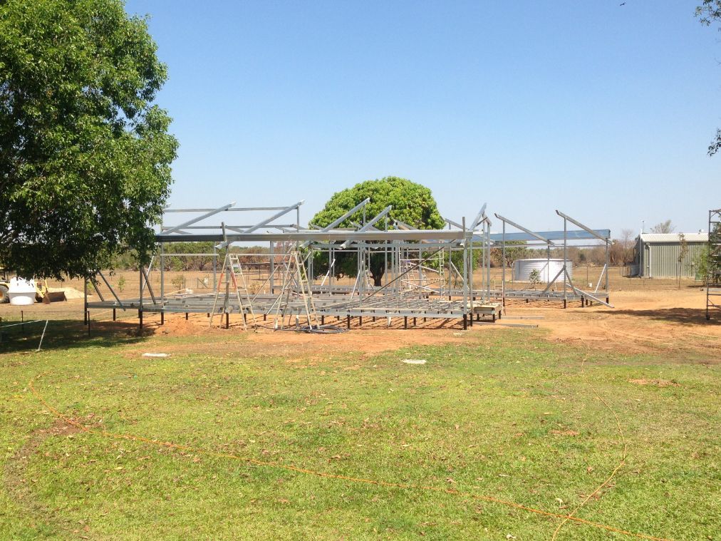 A large metal structure is being built in a grassy field — Local Builders in Yarrawonga, NT