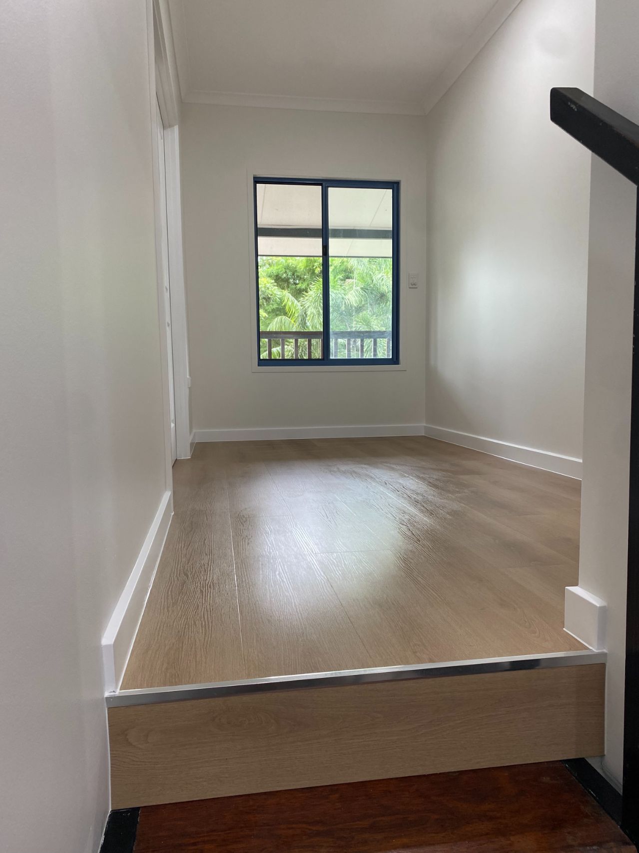 An empty room with hardwood floors and a window — Local Builders in Yarrawonga, NT