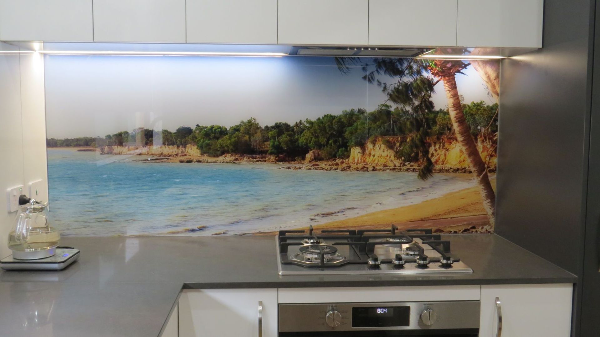 A kitchen with a stove top oven and a picture of a beach on the wall — Local Builders in Yarrawonga, NT