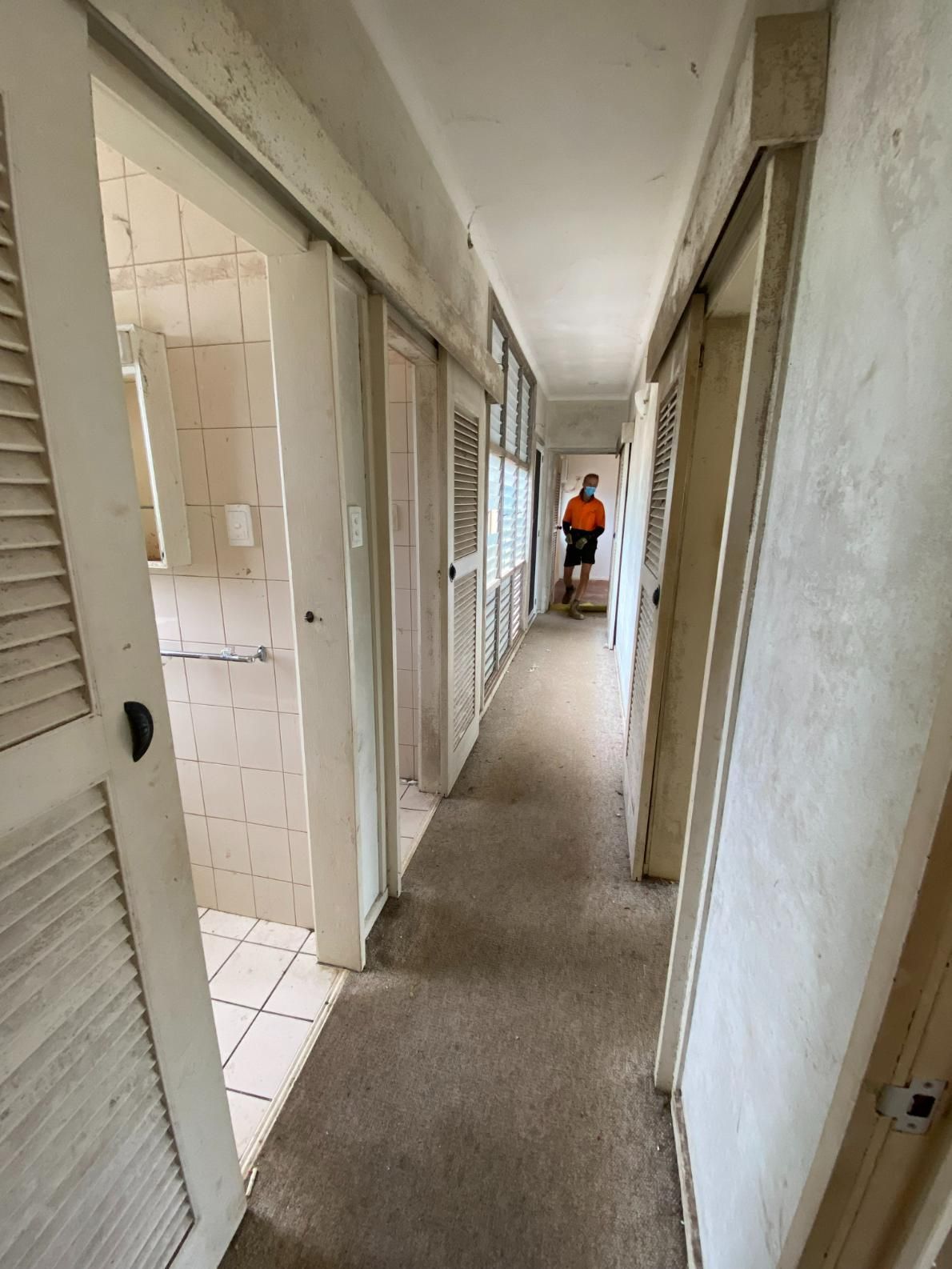 A Long Hallway With Sliding Doors and a Person Standing in the Middle of It — New Home Builders in Yarrawonga, NT