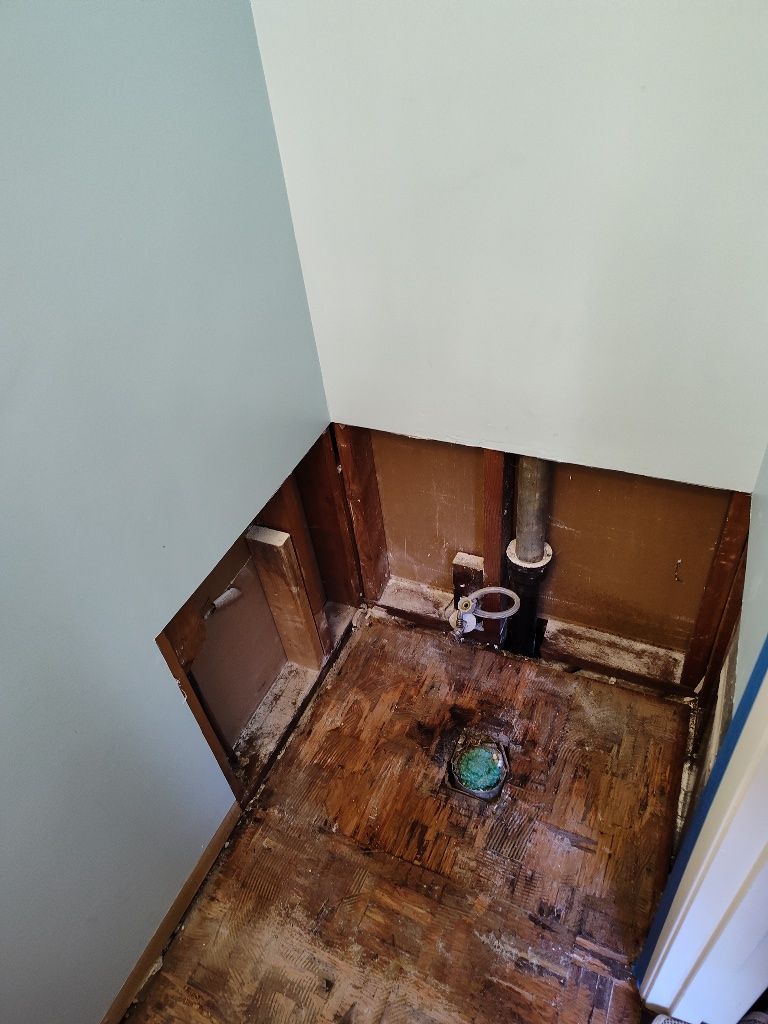 A bathroom with a hole in the wall and a hole in the floor.