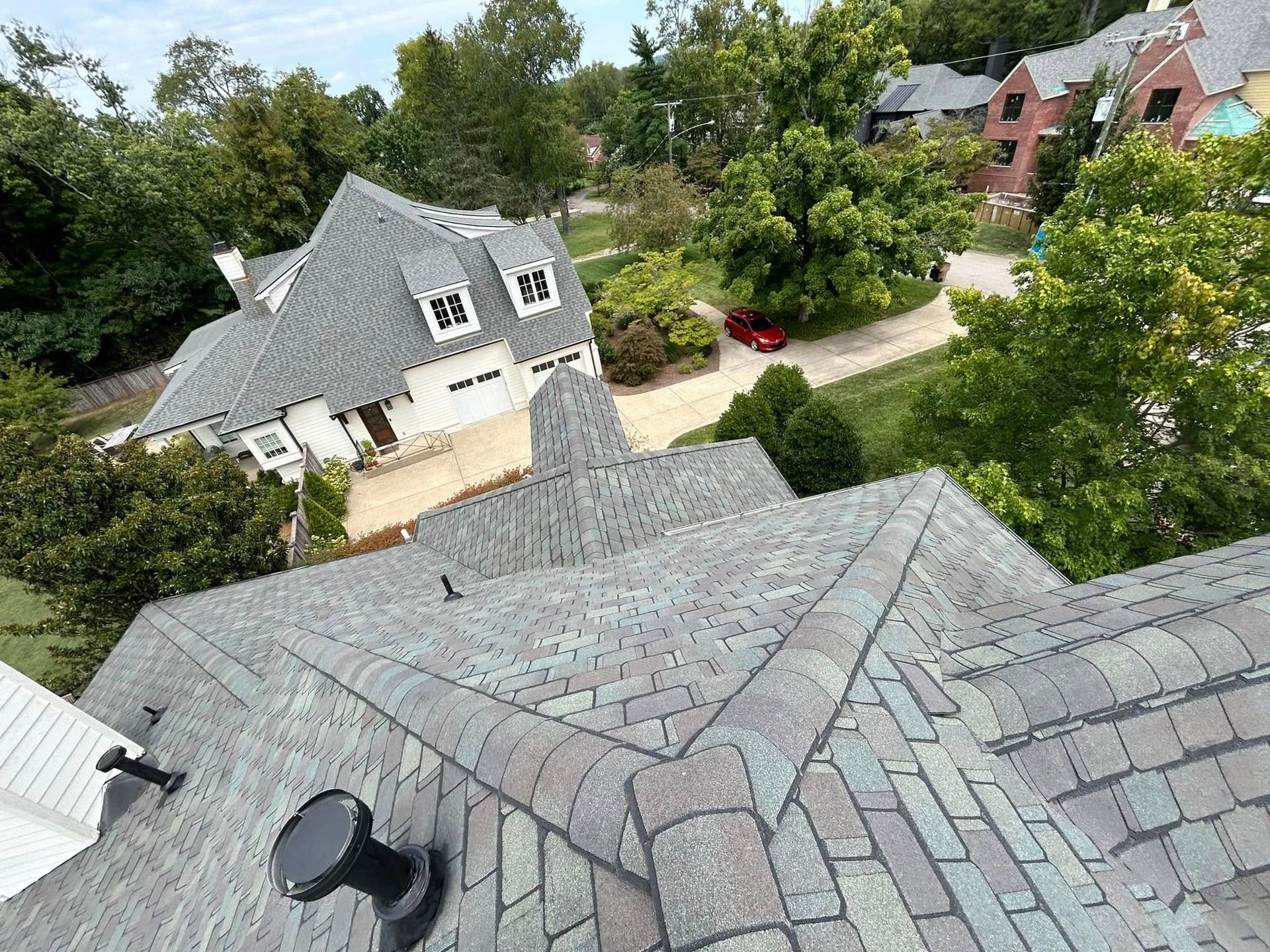 An aerial view of a roof of a house with trees in the background.