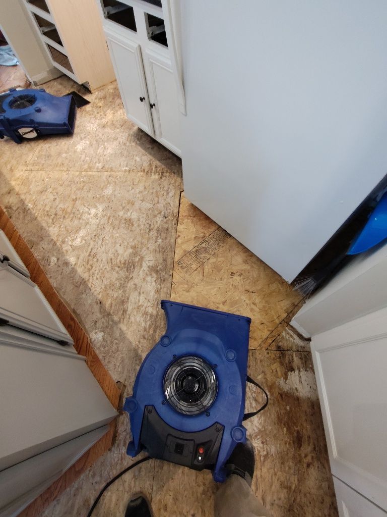 A blue blower is sitting on a tiled floor in a kitchen.