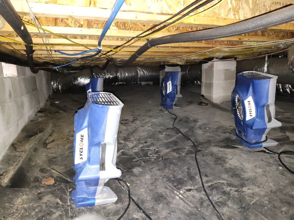 A bunch of fans are sitting under a ceiling in a basement.