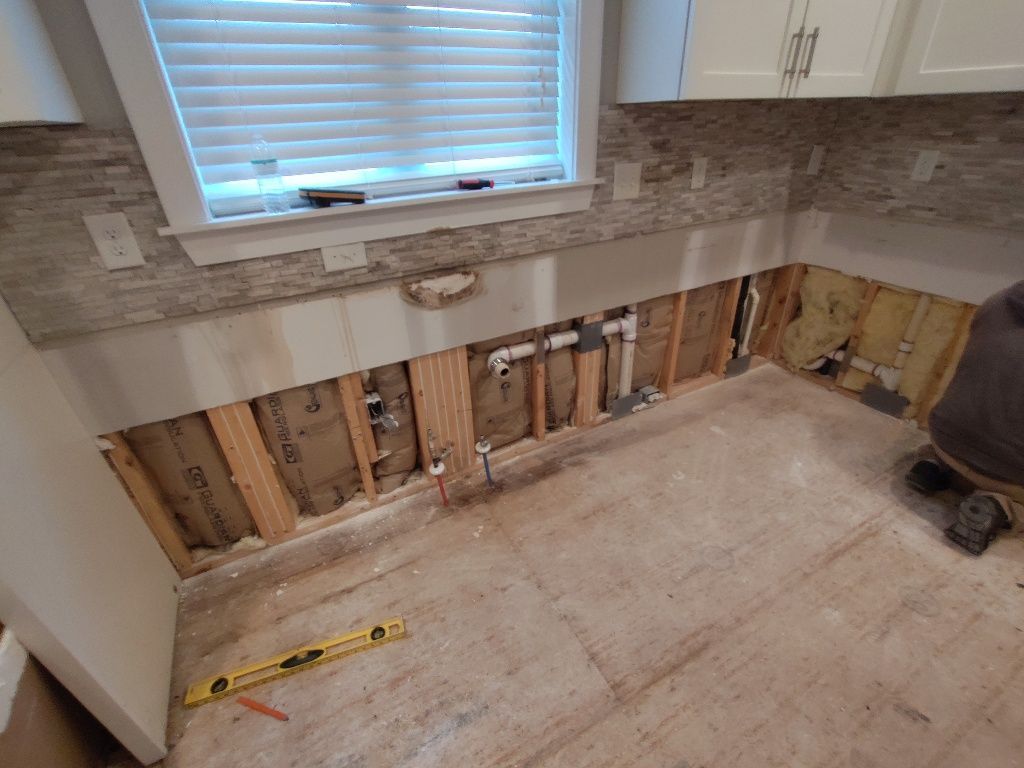 A bathroom under construction with a window and a level on the floor.