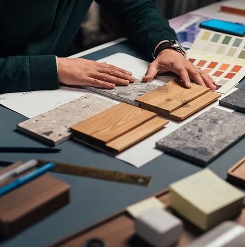 A person is sitting at a table looking at samples of wood and marble.